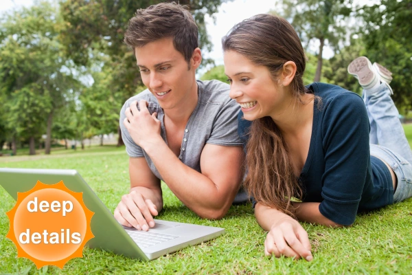 A couple on the grass looking at laptop together