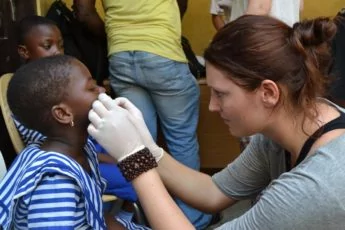 Volunteer woman doctor treating a child overseas in Ghana.