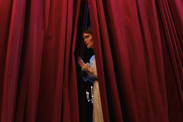 Woman behind red curtain on center stage