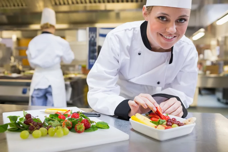 Chef preparing a fresh fruit bowl at a fancy restaurant.